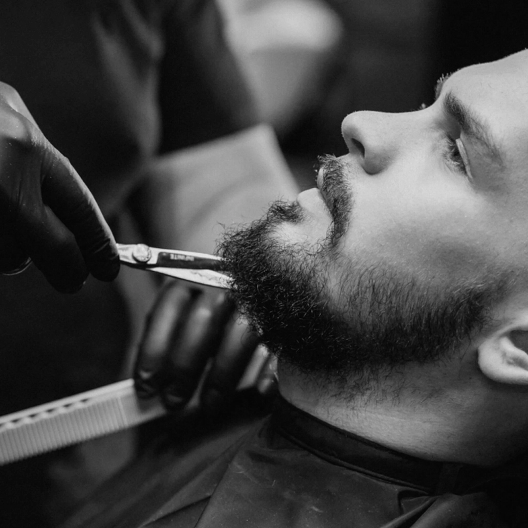 Barber shaping a beard with a comb and scissors